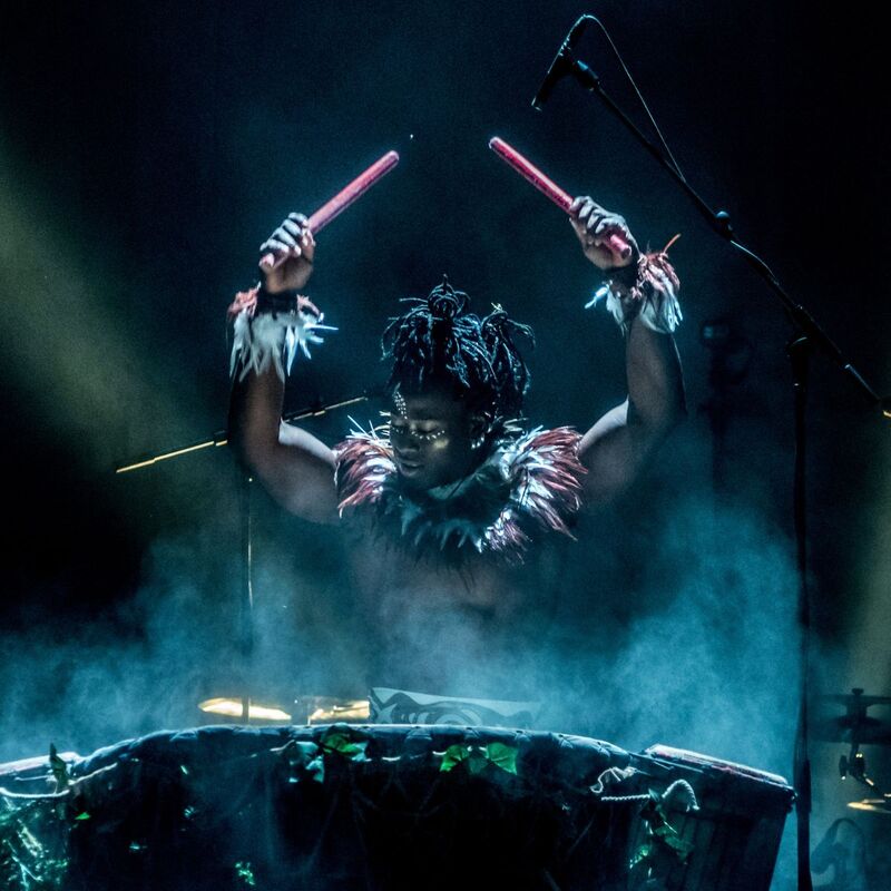 A drummer wearing a feathery neck piece