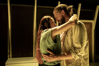 A man and a woman stand holding each other looking into each other's eyes