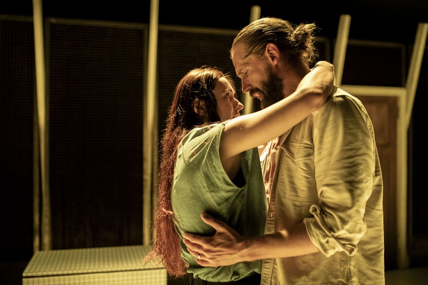 A man and a woman stand holding each other looking into each other's eyes