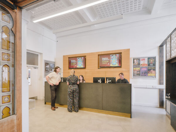 Two people stand at a grey counter to purchase tickets from the Brighton Dome ticket office