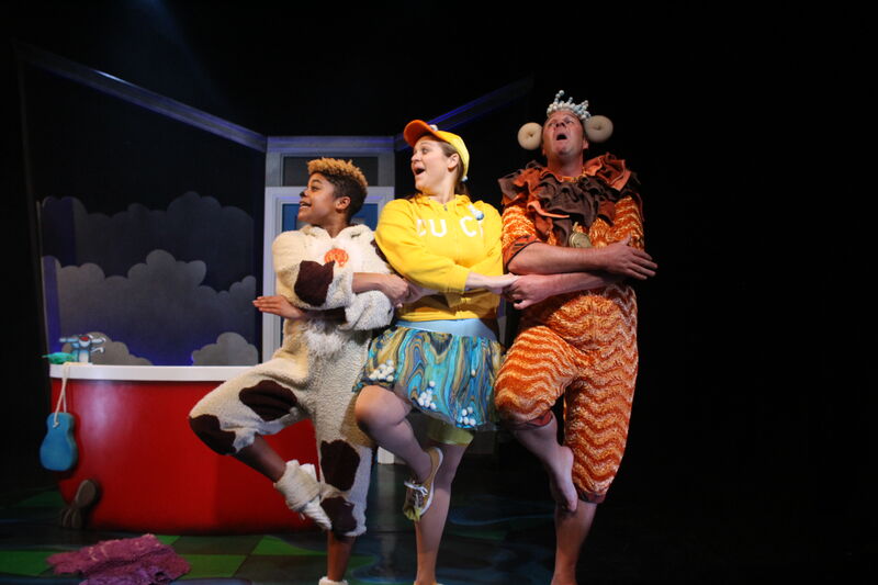 Actors dressed in animal costumes dance in a line holding hands