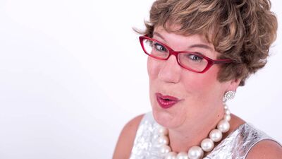 Lorraine Bowen in a silver dress and red glasses singing