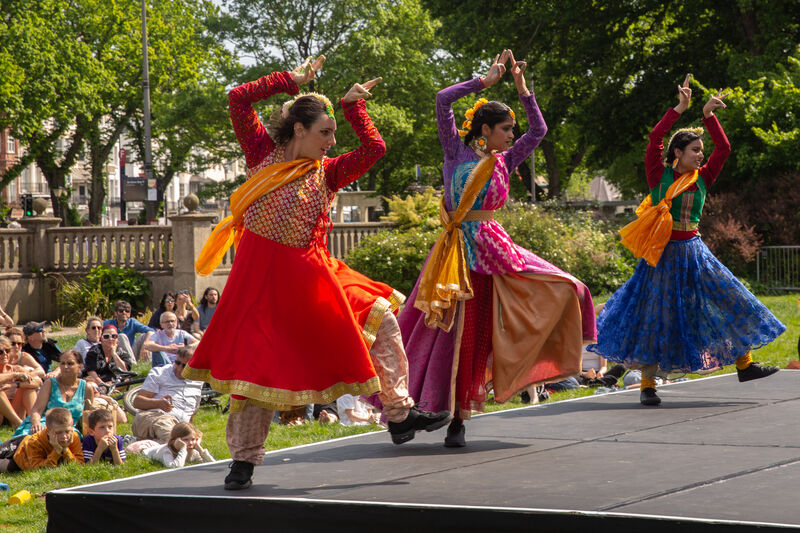 Three dancers in colourful outfits performing outside 