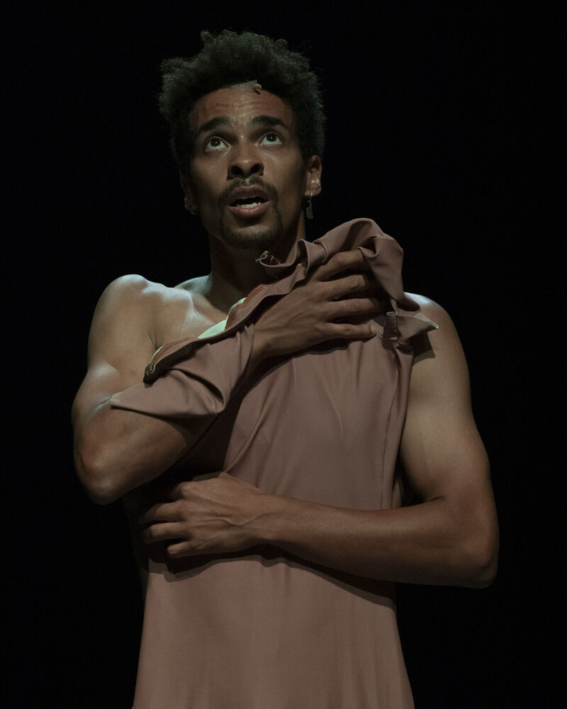 Liam Fancis holding a nude unitard over his body with his eyes raised to the ceiling.