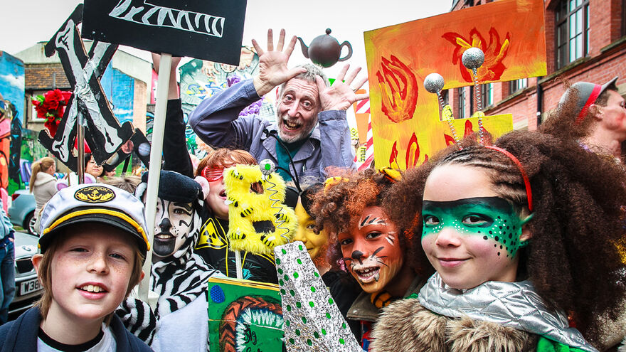 Children dressed up with facepaints pose with Michael Rosen