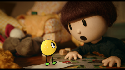 A puppet of a young person looks at an animated yellow blob creature. The puppet looks shocked