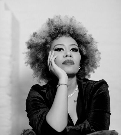 Emili Sande poses with her chin resting on her right hand. She is looking slightly down and not smiling.