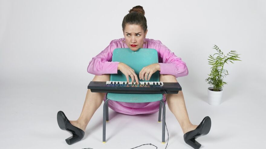 Rachel Blackman sitting playing a mini keyboard on a blue chair