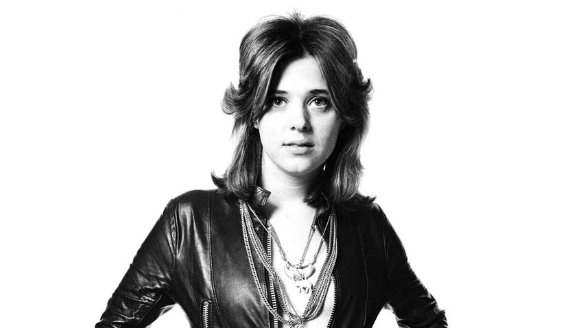 woman in black and white image with leather jacket and chains stares into camera