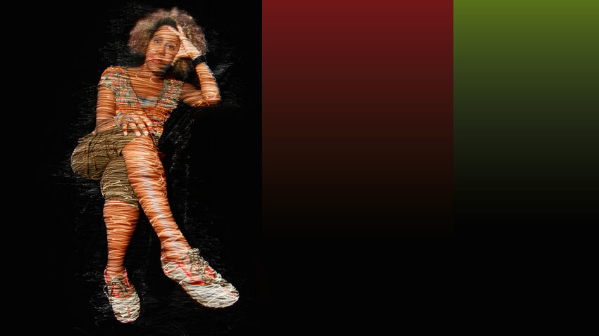 A black woman sitting in a relaxed pose with her left arm propping up her head and her legs crossed