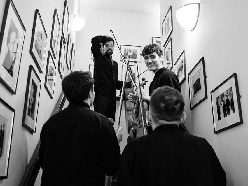 Atenea Quartet dressed for a concert and holding their instruments, smiling as they walk up stairs