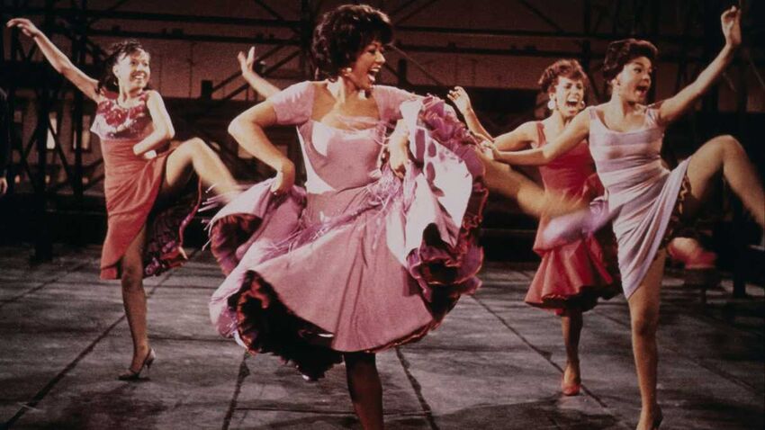 five women in dresses are dancing and smiling