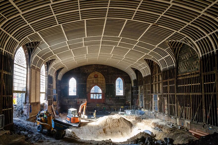 Interior of Corn Exchange with floor dug up and machinery in place. You can see the exposed beams of the roof.