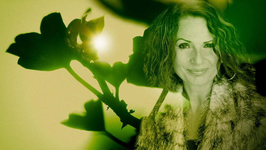 Image of a woman in front of a close of image of a flower with the sun seeping through