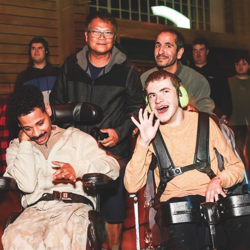 Two learning disabled people and their carers are in Brighton Dome Corn Exchange at a Blue Camel Club night. They are smiling and having a good time
