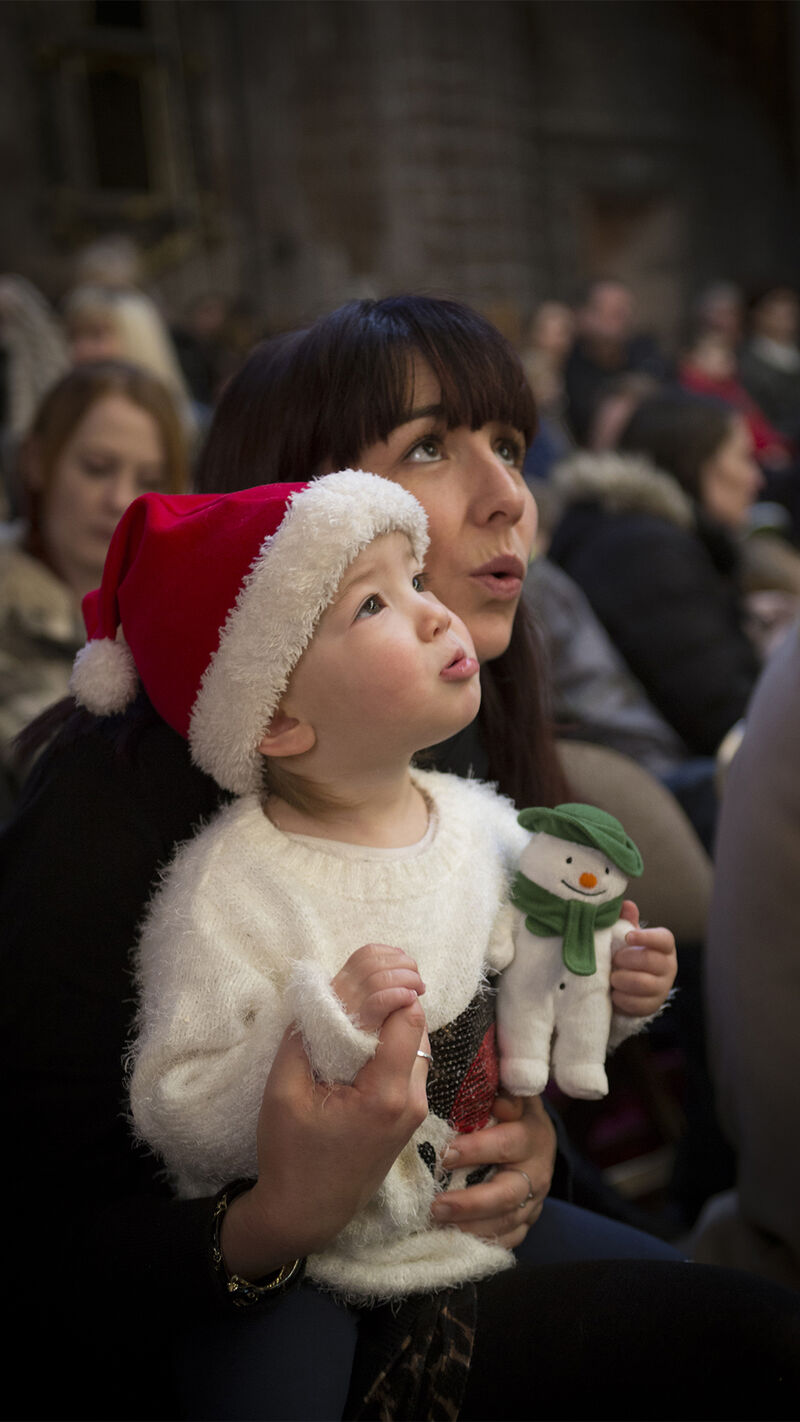 Kid wearing a christmas hat holding a snowman plushie toy