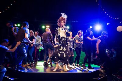 Ida Barr sings on stage surrounded by people doing the conga