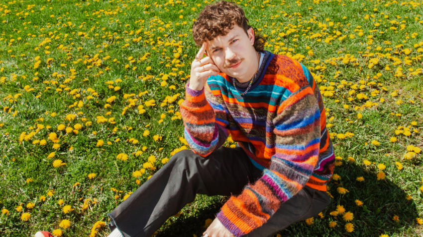 Kurtis Conner sitting in a field of dandelion flowers