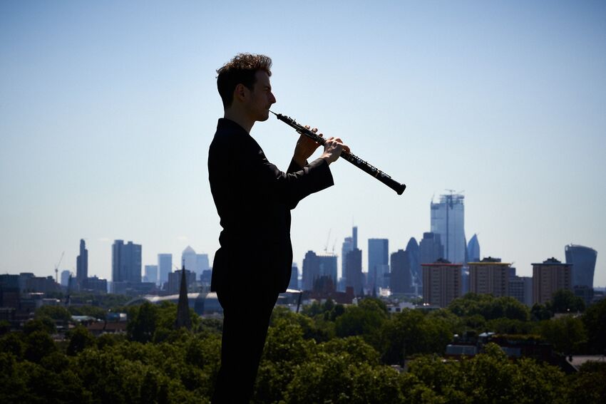Olivier Stankiewicz performing in a park in front of a London skyline