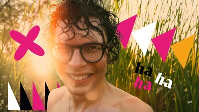Simon Amstell in tall grass smiling to the camera with wet hair and his shoulders exposed with Brighton Dome Comedy Festival branding
