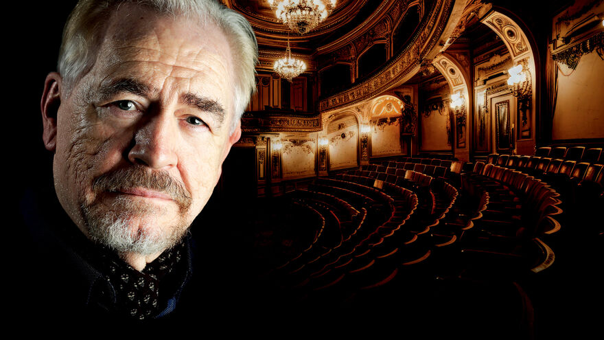 Brian Cox standing in front of a theatre with chairs