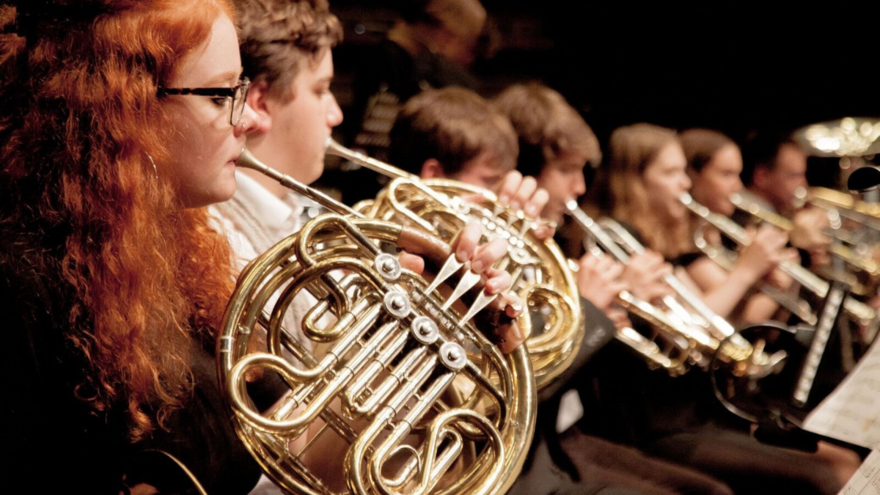 A row of young people playing brass instruments