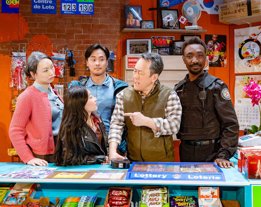 The cast of Kim's Convenience stood behind a light blue counter