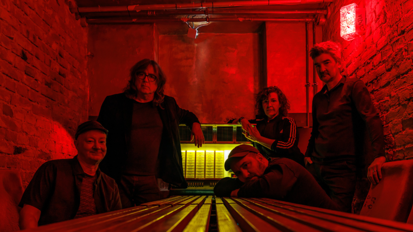 group image of The Magnetic Fields in a red room with red lighting 
