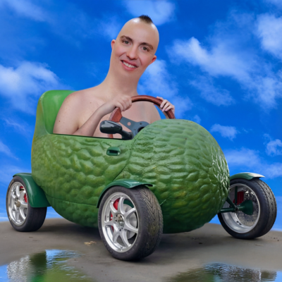 Sam Campbell with an edited, shaved head smiles while sitting in a small, avocado-shaped green car. The car has shiny silver wheels and is parked on concrete with puddles. Behind him is a bright blue sky with soft, scattered clouds