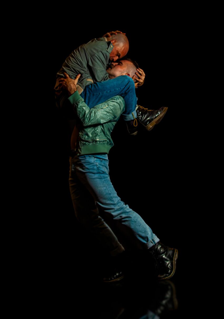 Two men kissing, one holding the other on his shoulders
