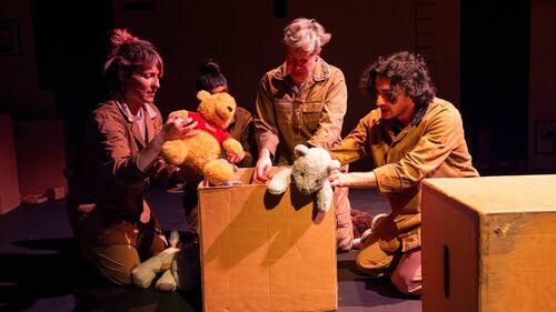 Three adults puppeteering soft toys on top of a cardboard box
