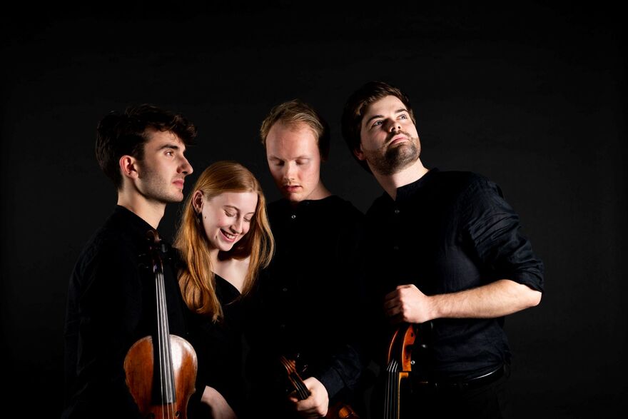 Four people standing in black outfits over a black background, each holding a string instrument