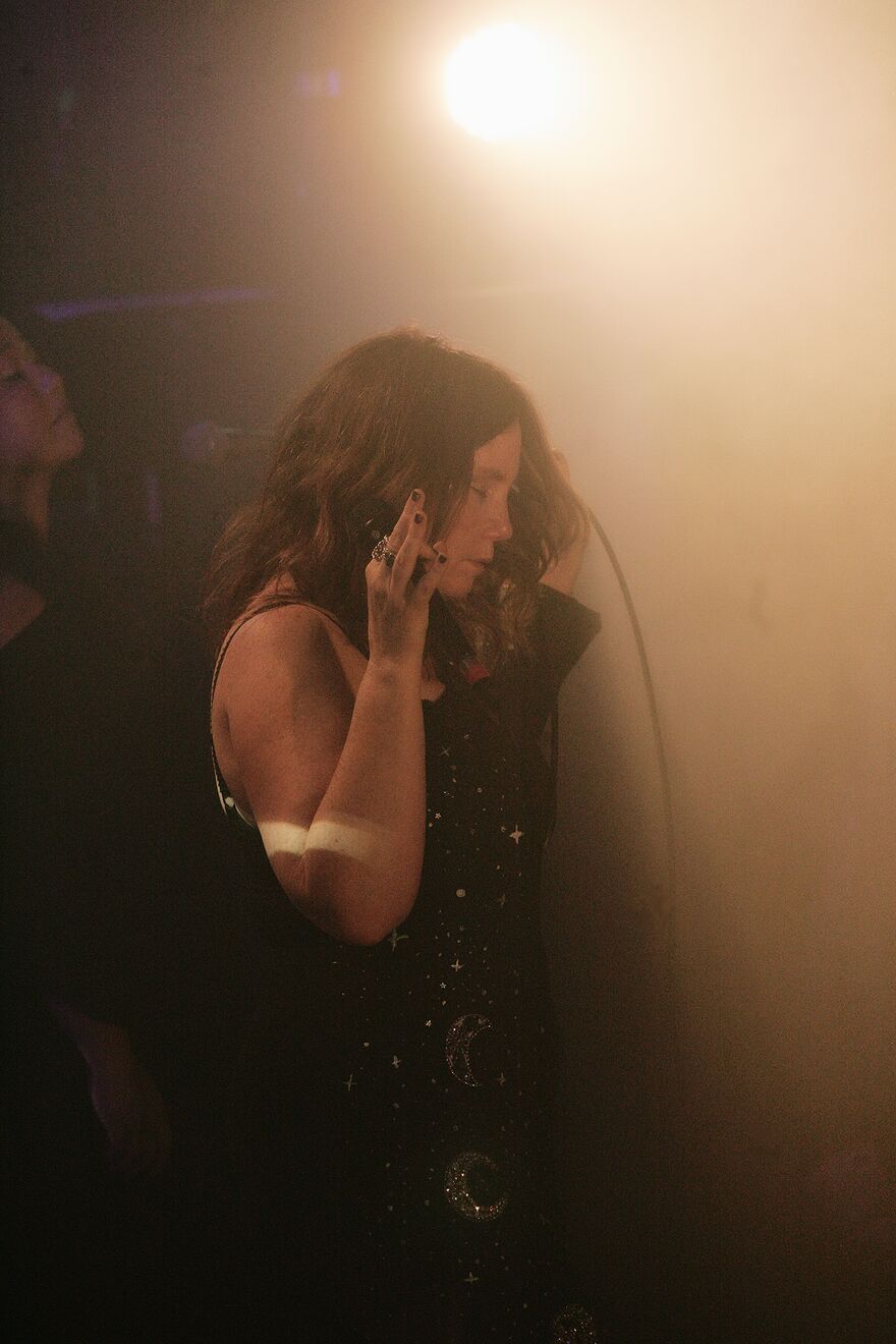 Frazey Ford singing in a dark room with her hand up to her face