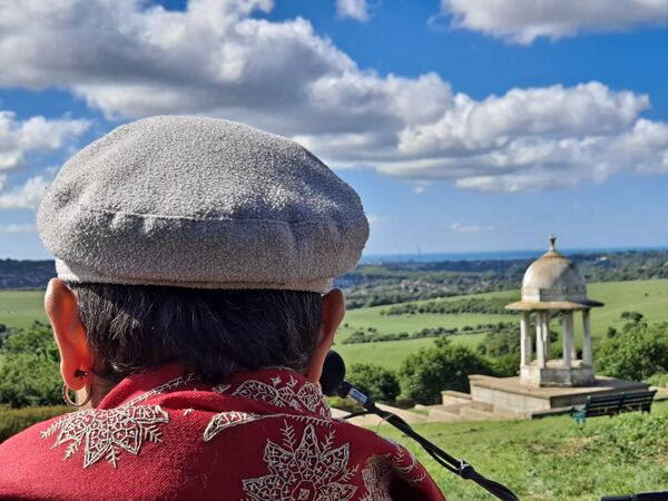 A figure wearing a hat looks over the downs and the Chatri Memorial