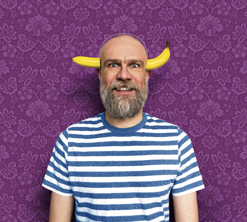 Olaf Fafalel standing over a purple background with a banana on his head