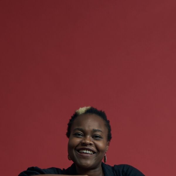 Tendai, a black women with short black hair and a bleached streak through it, smiles widely