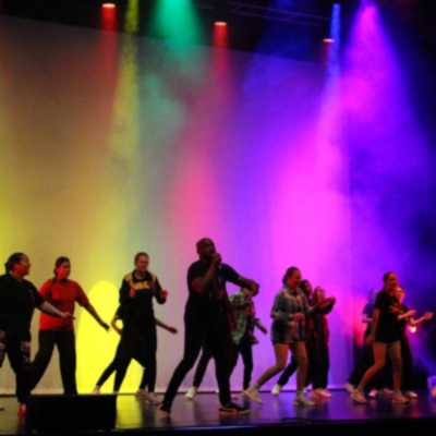 Dancers dancing in front of multi-colour lights
