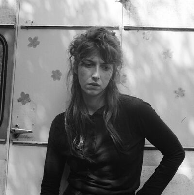 Aldous Harding standing looking down with her arm on her hip