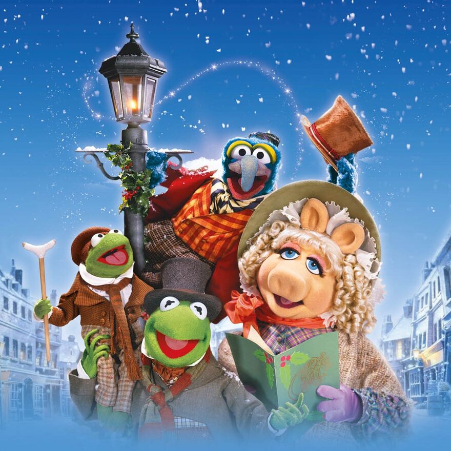 four puppet characters are in the street with one of them holding open a book for Christmas carols