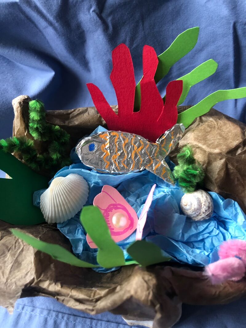 A hand crafted rock pool with water, seaweed and a fish made from colourful cardboard