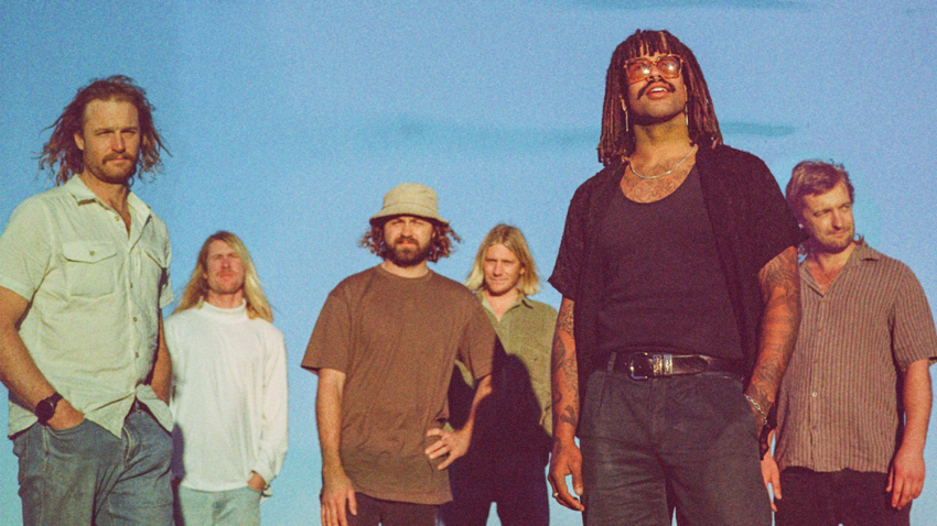 6 men in casual clothing standing in front of a blue sky