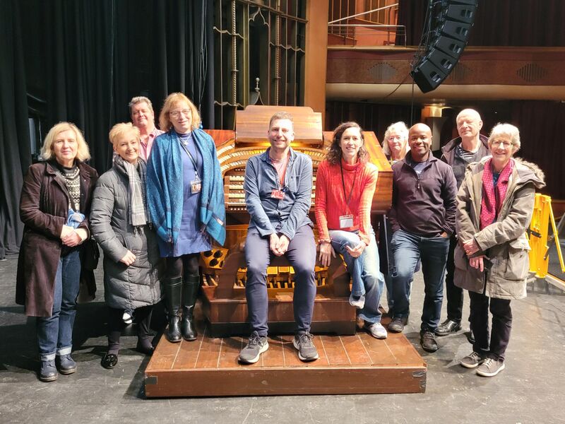 A group of volunteers stand around the Brighton Dome organ console on the Brighton Dome stage