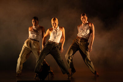 The 3 female dancers in Femme Fatale in a triangle formation. They are wearing formal clothes.