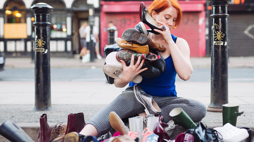 When Did You Stop Dancing? performer sitting on the ground surrounded by piles of shoes