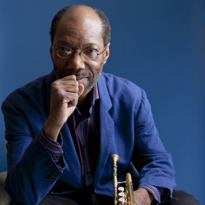 Charles Tolliver sitting casually and holding a trumpet