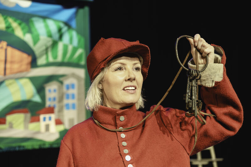 Victoria Melody on stage wearing a medeival royalist costume holding up a set of rusty keys