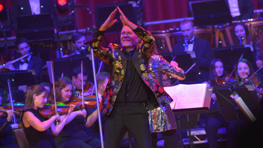 man stands on a stage with an orchestra