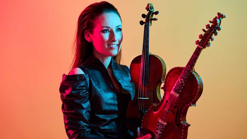 woman smiles and holds two instruments in her hand