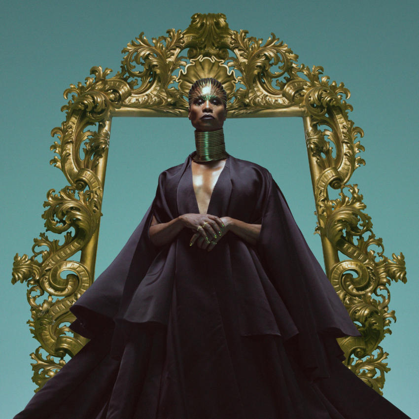 Billy Porter standing inside a big golden frame, wearing a flowing black robe and golden crown