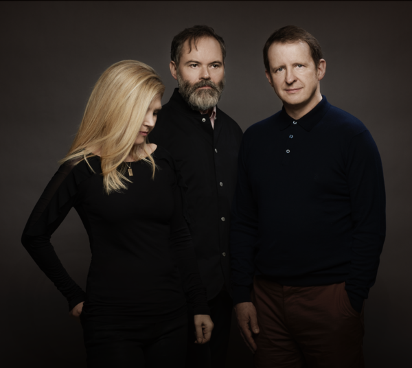 The three members of Saint Etienne stand against a brown background